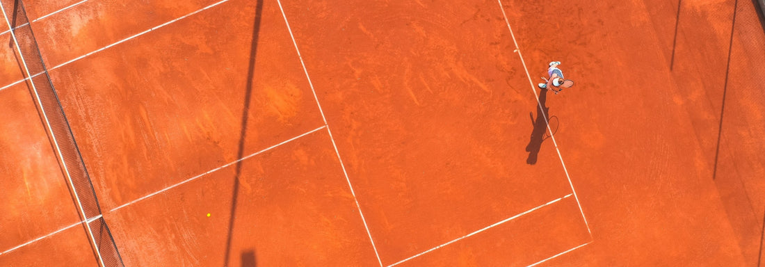 Tennis player on a red clay court from an aerial perspective