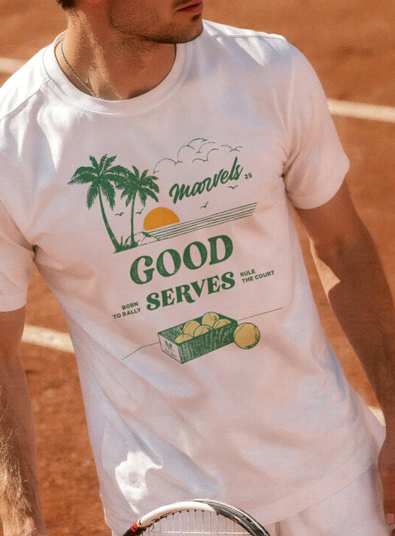 Man wearing a green t-shirt with text and graphics, standing in front of a scenic coastal town. Title text reads, 