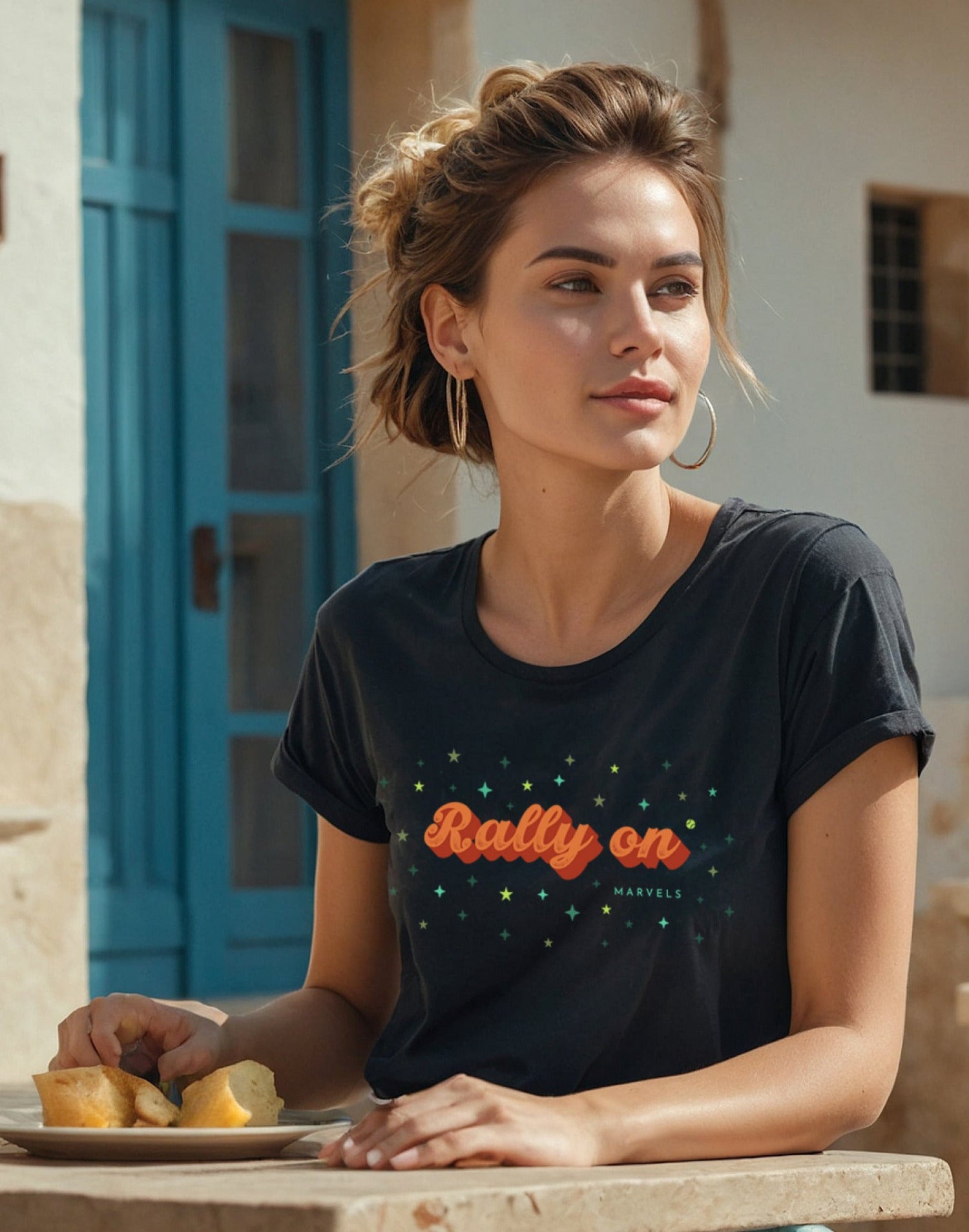 Woman wearing a black t-shirt with 'Rally on' text, sitting outdoors.