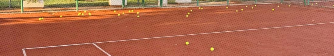 Clay surface tennis court with tennis balls on the ground