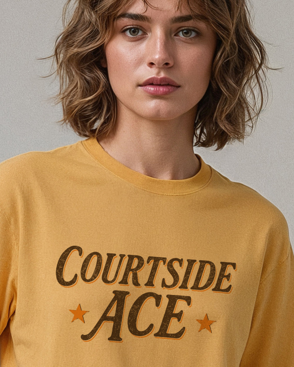 Person wearing a yellow gold t-shirt with 'Courtside Ace' text and stars.