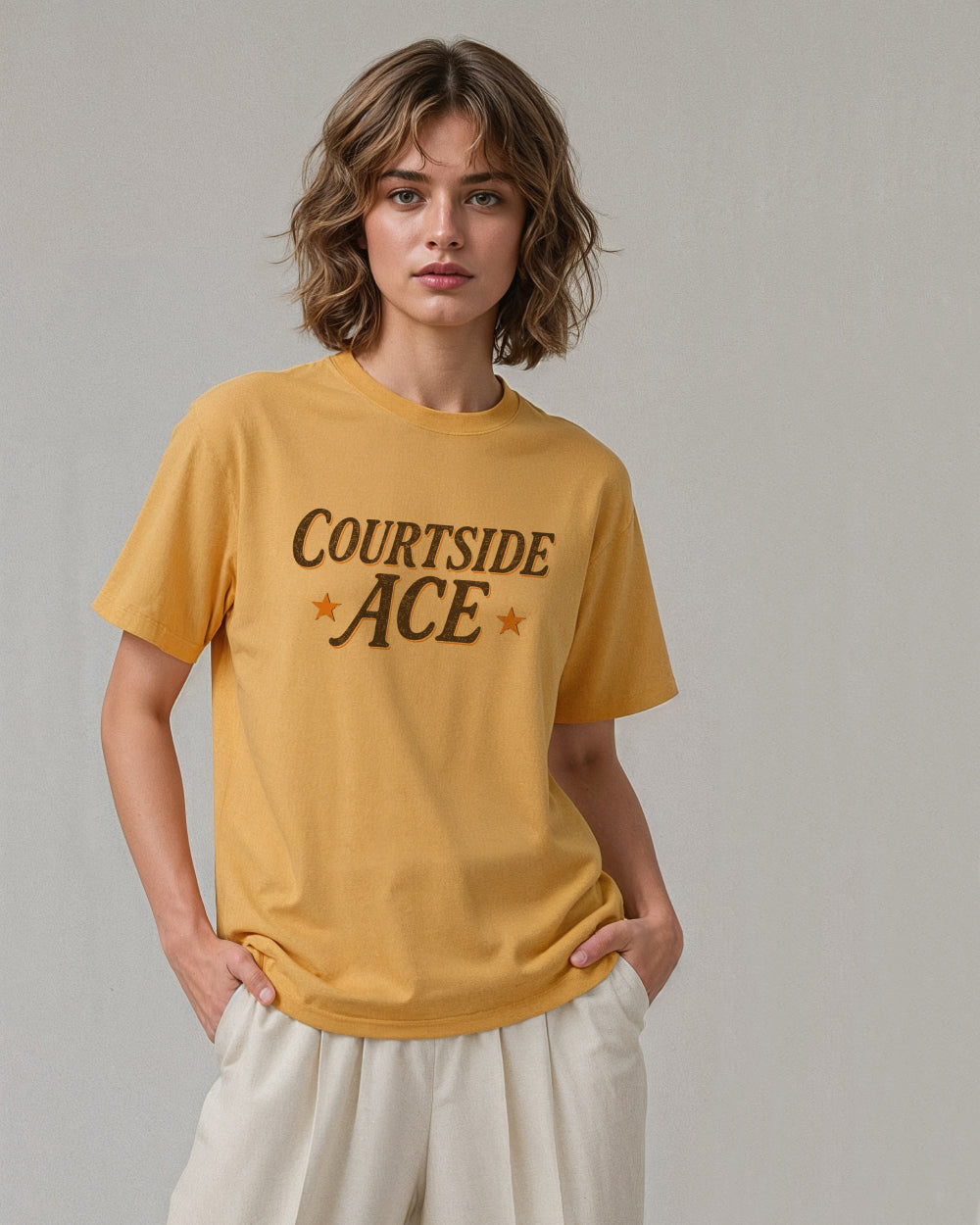 Person wearing a yellow gold t-shirt with 'Courtside Ace' text on a plain background