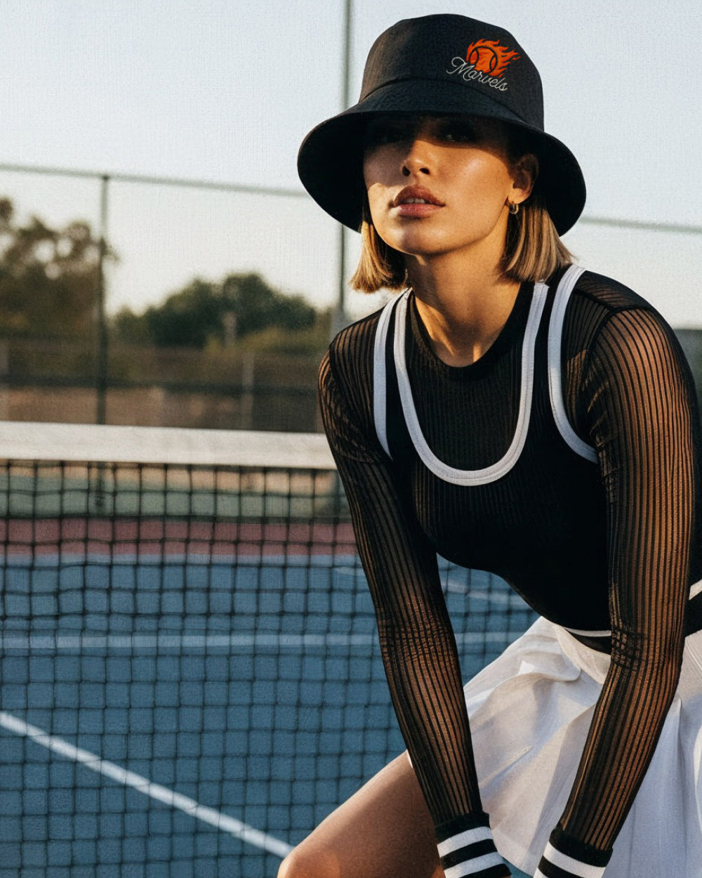 Person wearing a black bucket hat and black outfit on a tennis court