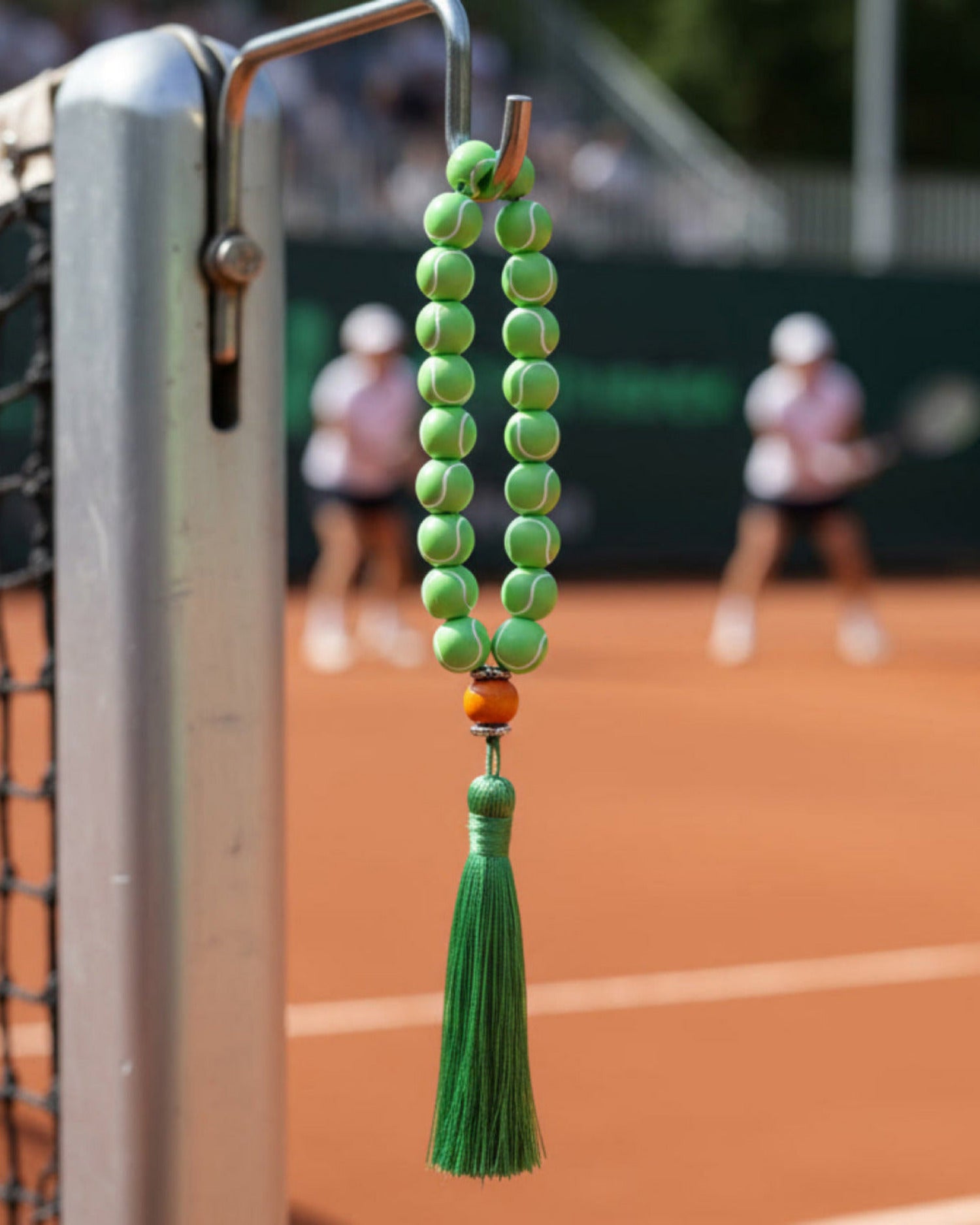 Decorative tennis ball prayer beads with tassel on a tennis court