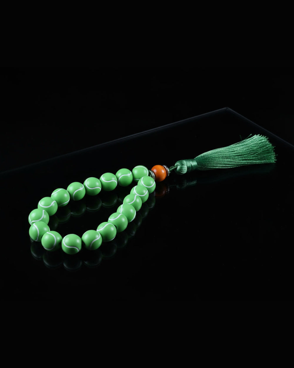 Green prayer beads with a tassel on a black background
