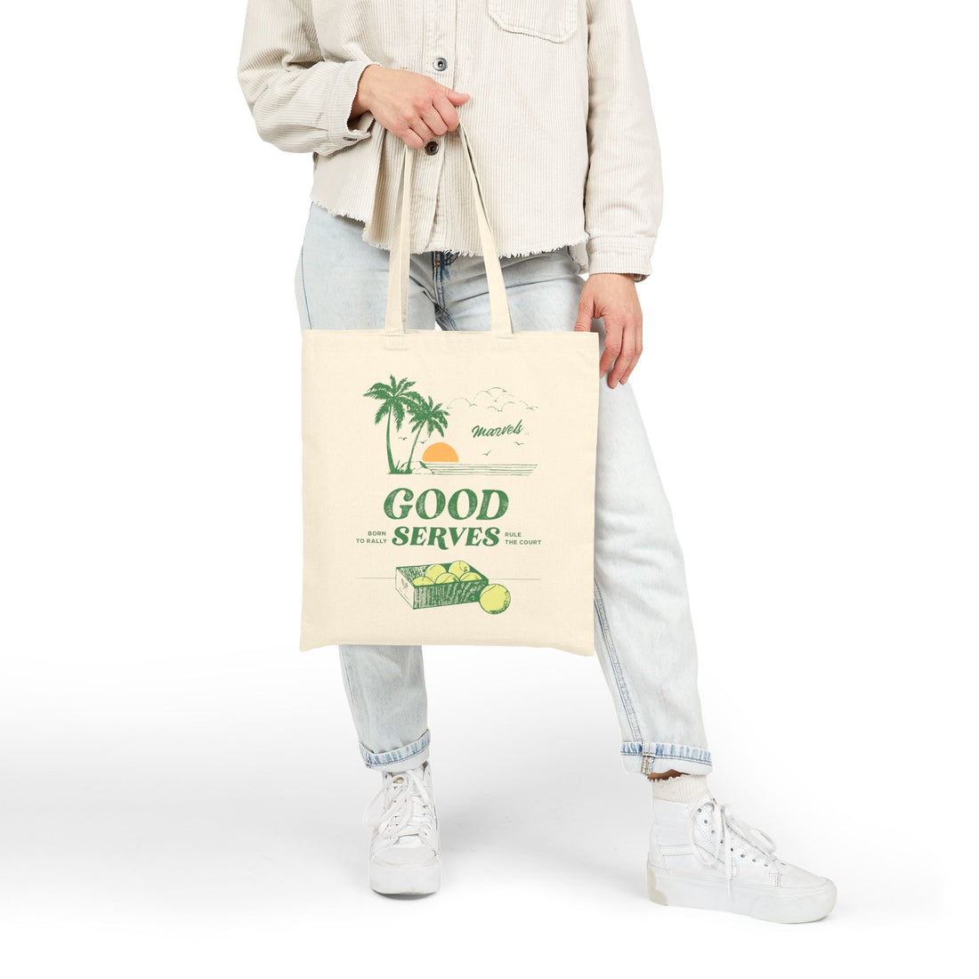 Person holding a tote bag with a palm trees graphic and text that reads 'Good Serves' on a white background