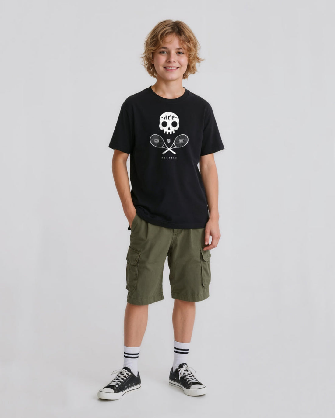 Child wearing a black t-shirt with a  skull and crossed tennis rackets graphic design and green cargo shorts on a white background