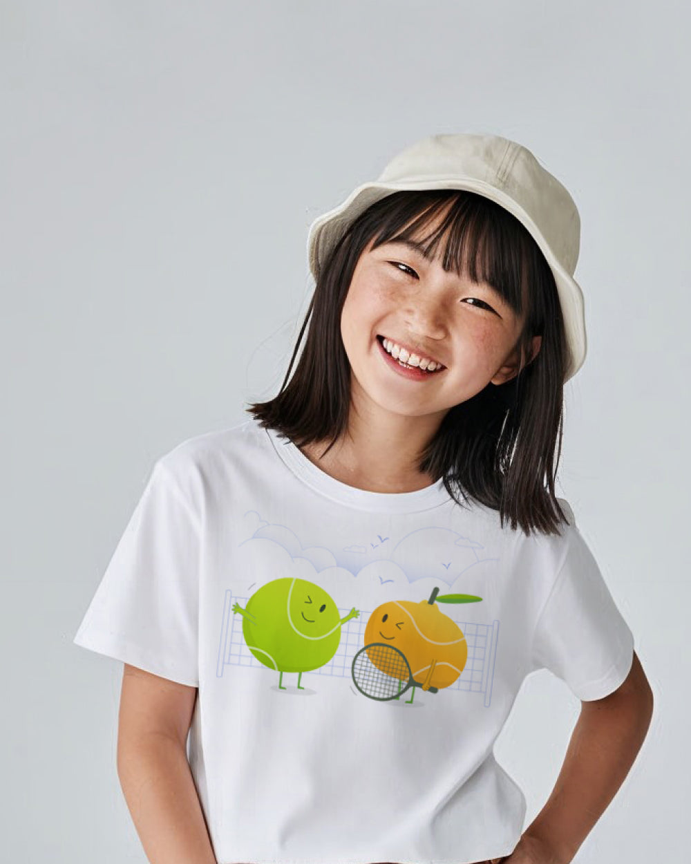 Child wearing a white t-shirt with cartoon tennis designs
