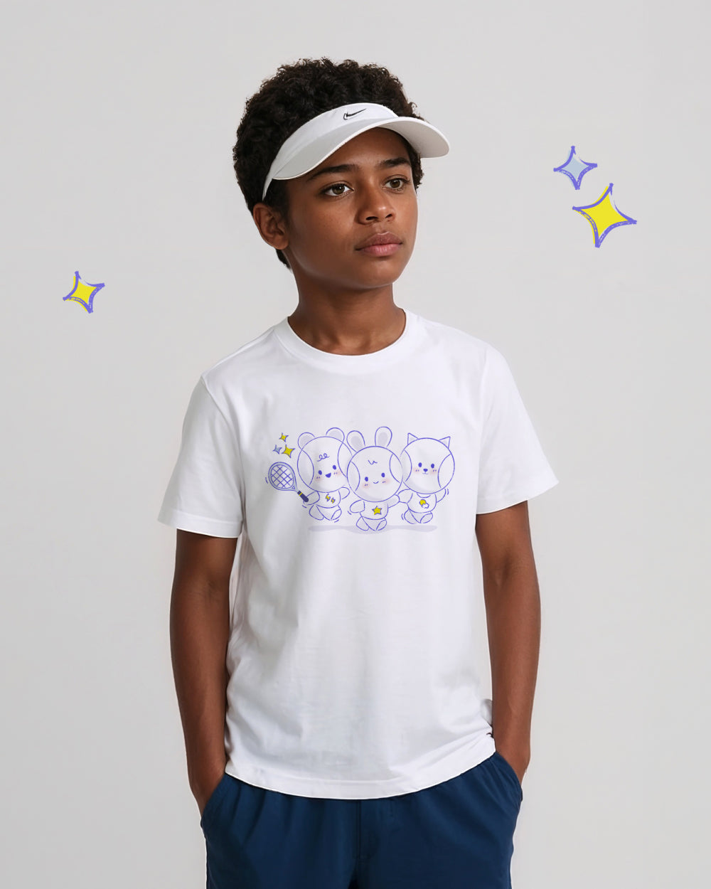 Child wearing a white t-shirt with cartoon tennis ball designs and a visor