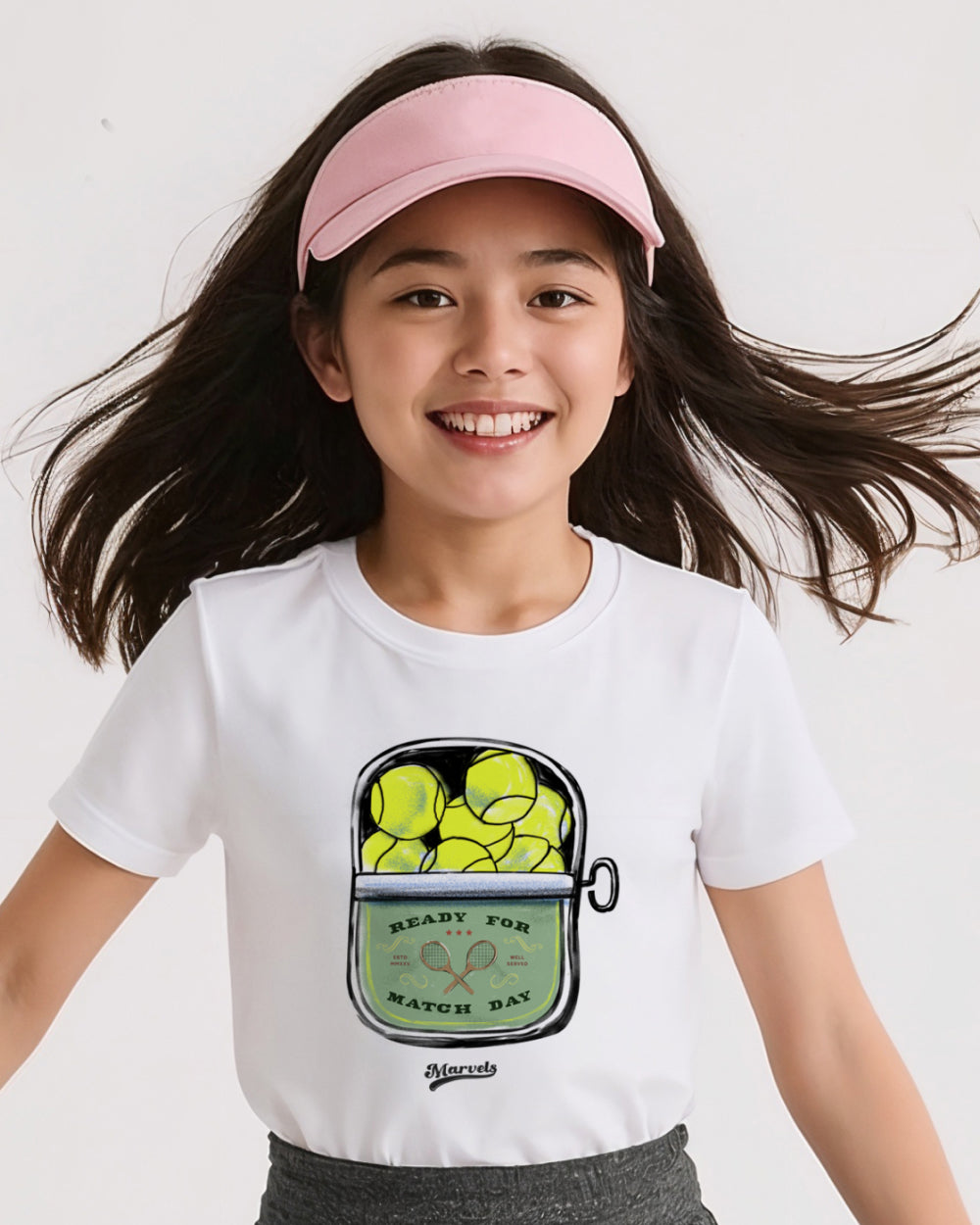 Child wearing a white t-shirt with a tennis-themed graphic and a pink visor.