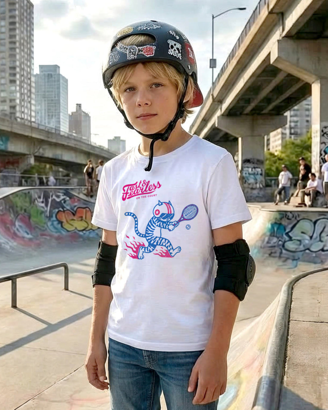 Boy at a skateboard park wearing a helmet and a white t-shirt with a tennis graphic