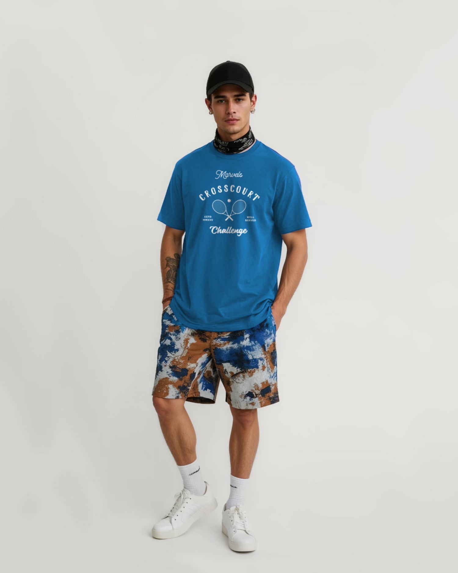 Person wearing a blue t-shirt with text and graphics, camouflage shorts, and white sneakers on a plain background
