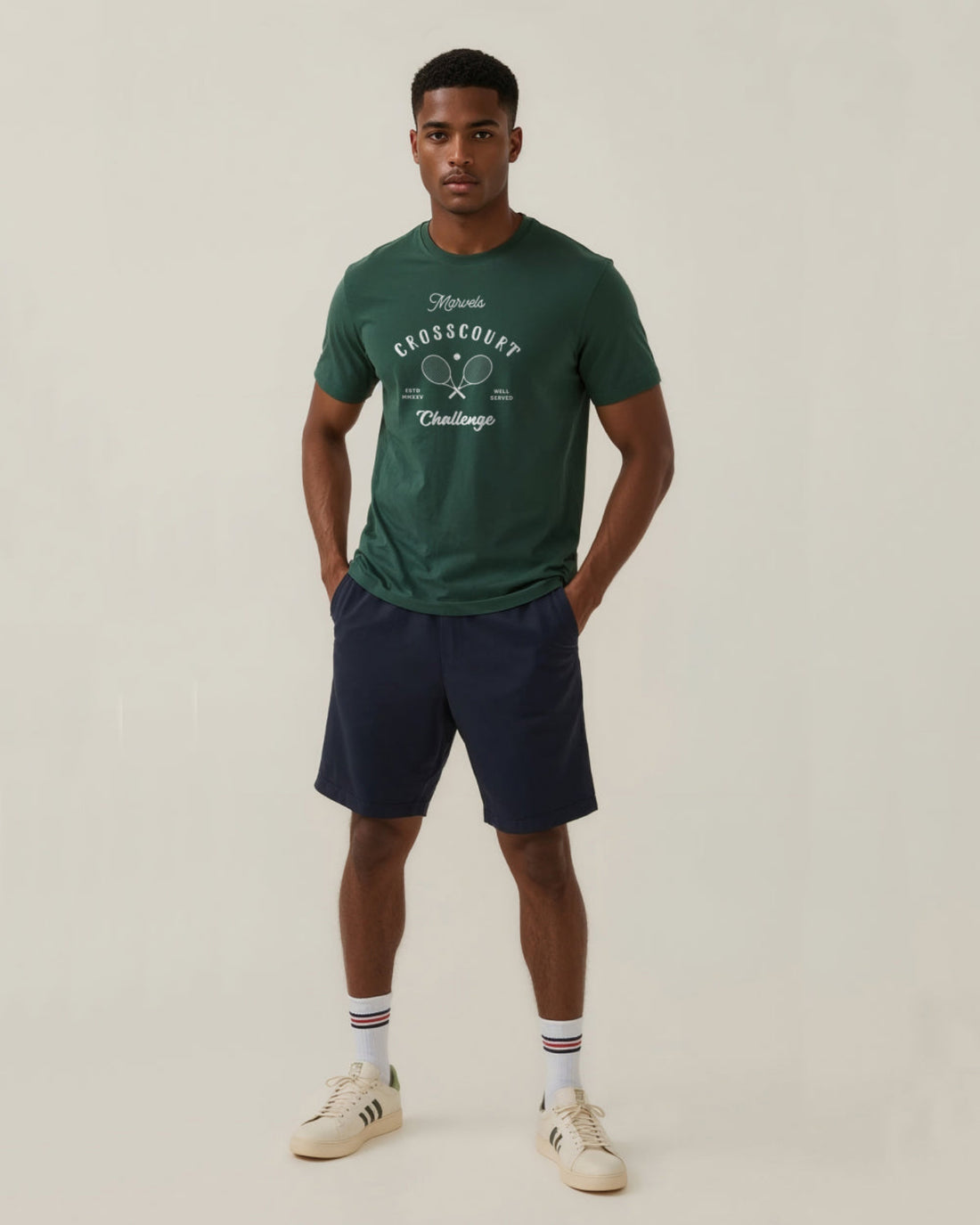 Man wearing a green tennis t-shirt with a graphic design and navy shorts on a light background