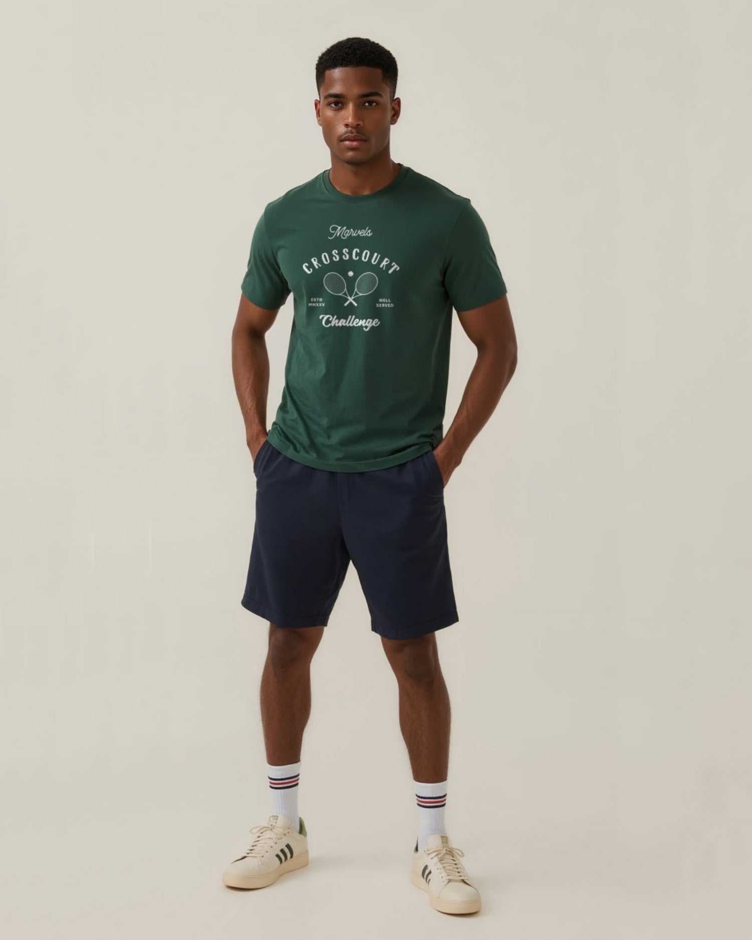 Man wearing a green tennis t-shirt with a graphic design and navy shorts on a light background