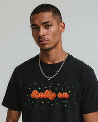 Man wearing a black t-shirt with 'Rally on' text and stars, standing against a plain background