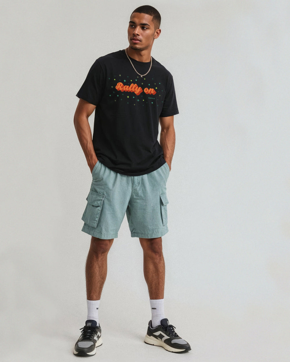 Man wearing a black t-shirt with text and light blue cargo shorts on a white background