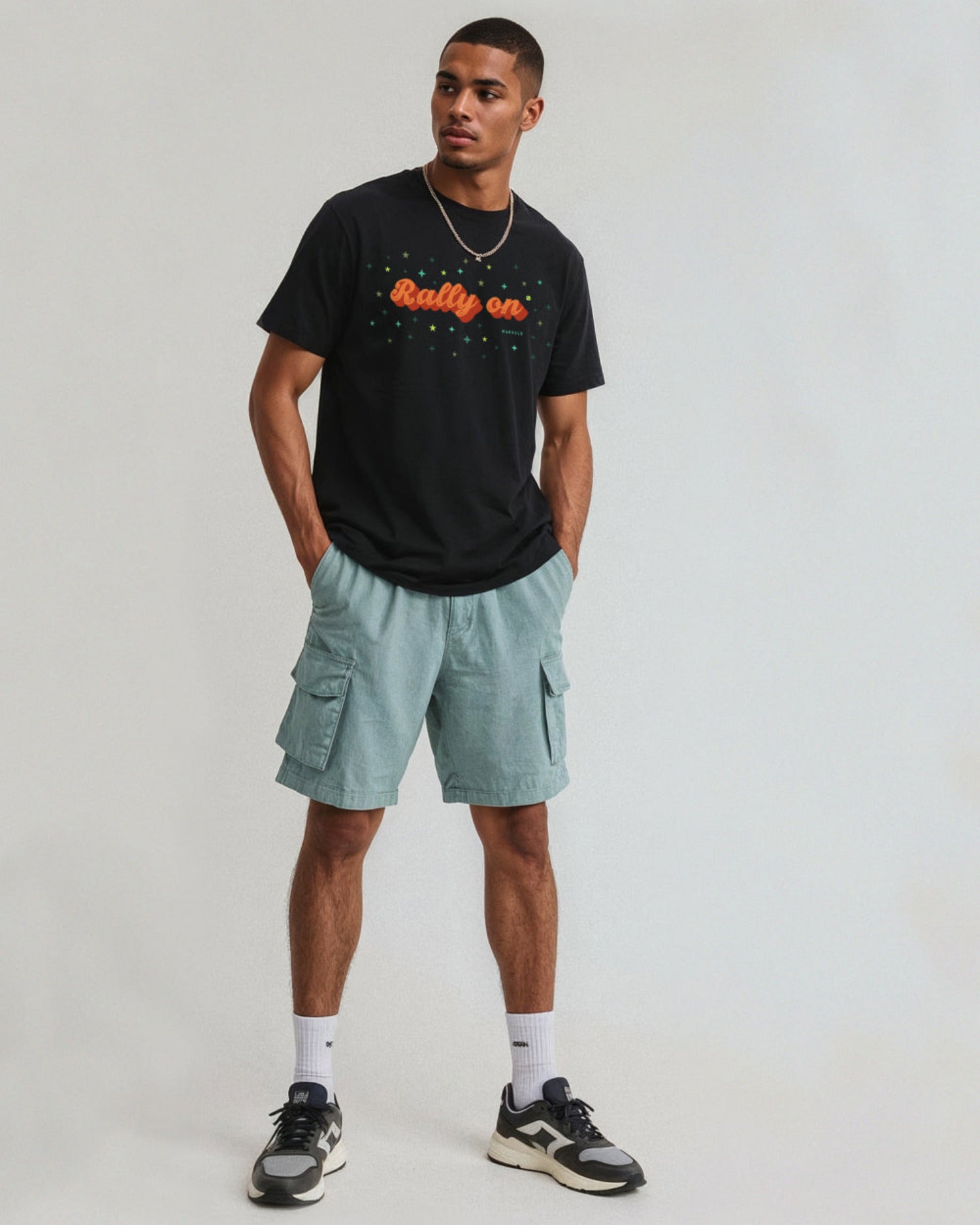 Man wearing a black t-shirt with text and light blue cargo shorts on a white background