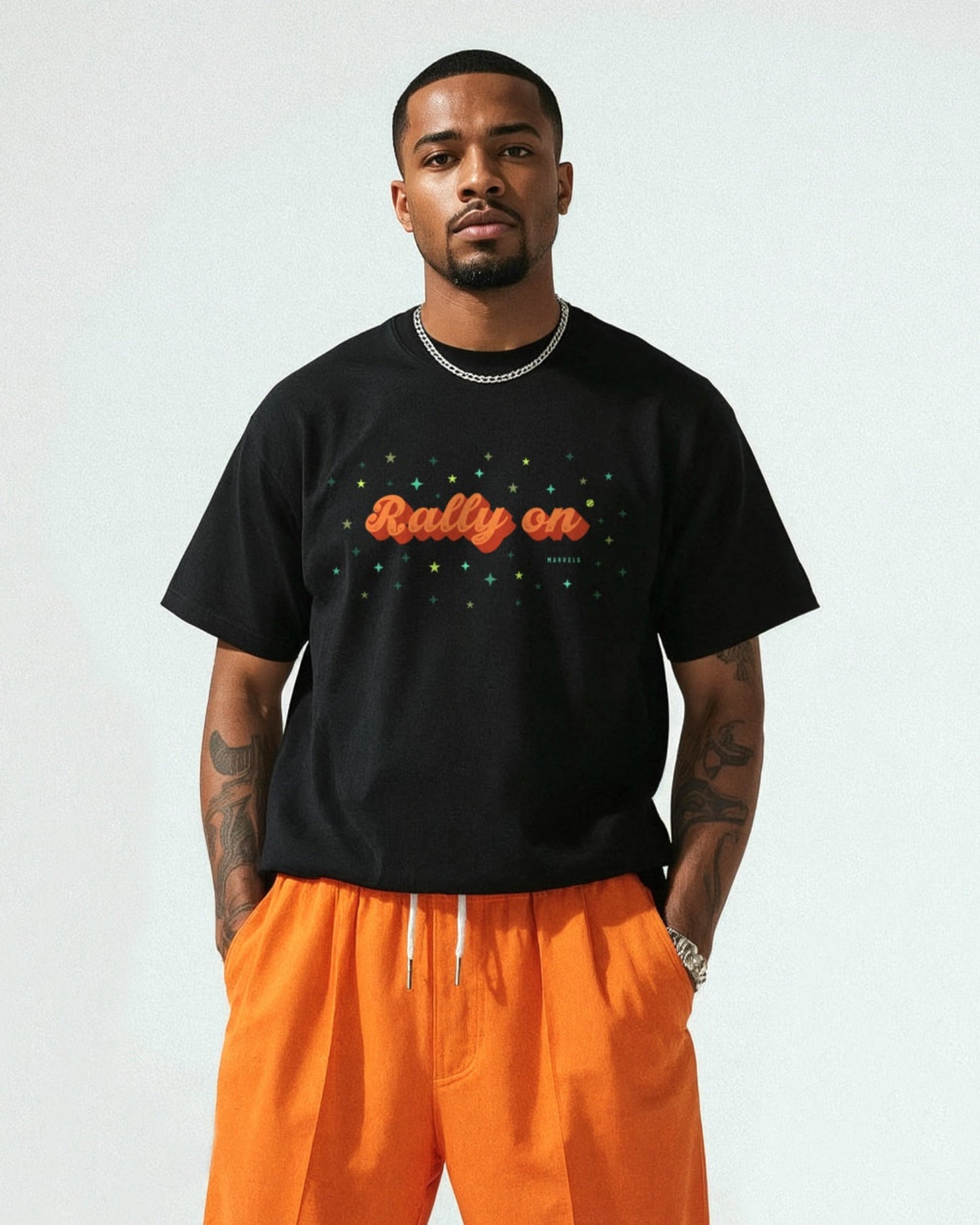 Man wearing a black t-shirt with 'Rally on' text and orange pants against a plain background