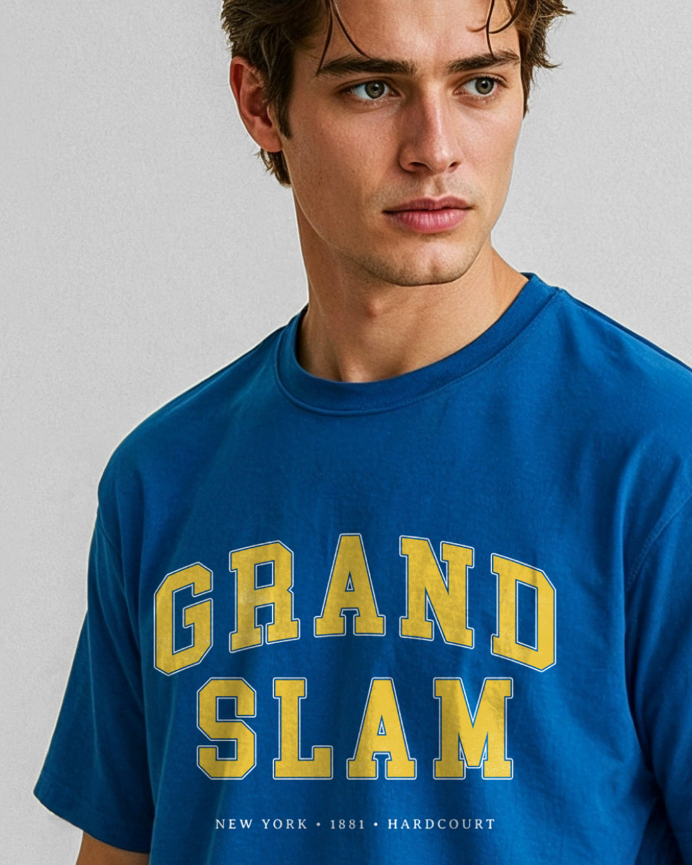 Man wearing a blue 'Grand Slam' t-shirt with yellow text on a gray background