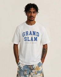 Man wearing a white t-shirt with 'Grand Slam' text on a beige background