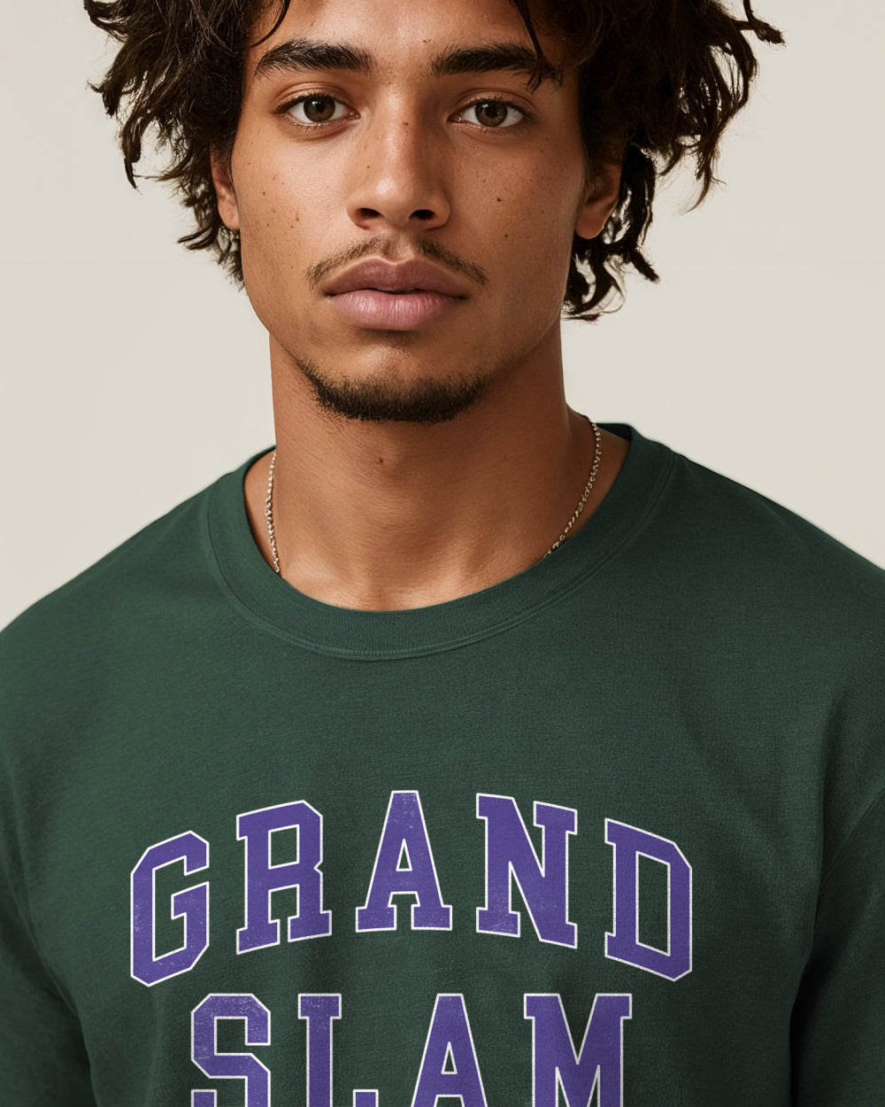 Man wearing a green sweatshirt with 'GRAND SLAM' text on a beige background