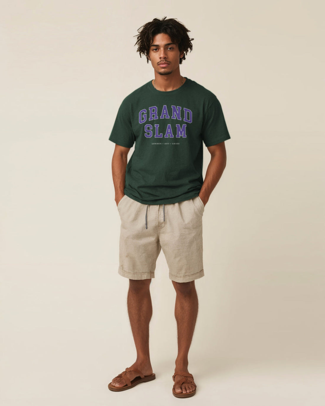 Man wearing a green 'Grand Slam' t-shirt and beige shorts on a plain background