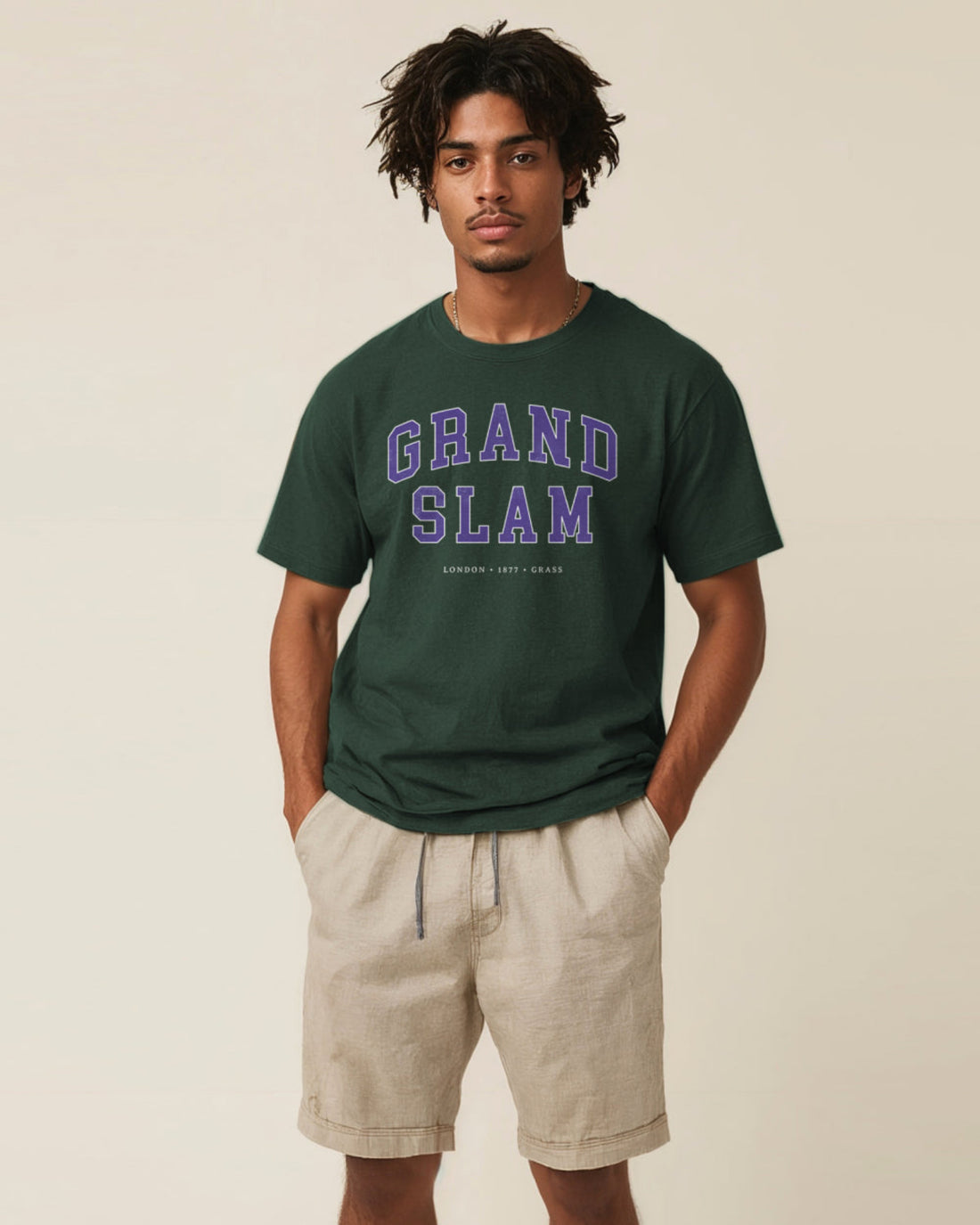 Man wearing a green 'Grand Slam' t-shirt and beige shorts on a beige background