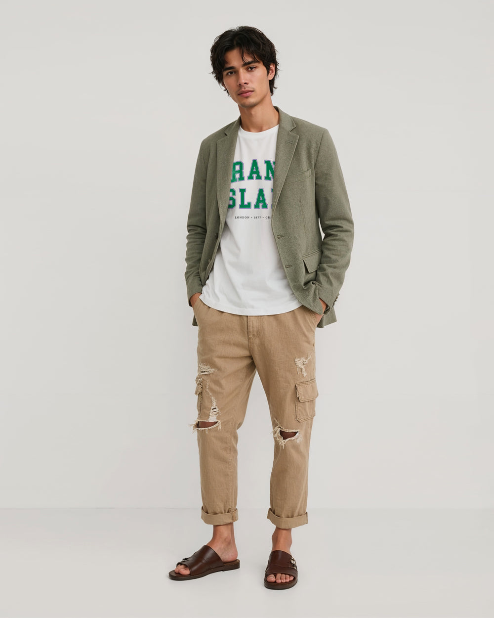 Man wearing a green blazer, white Grand Slam t-shirt with text, and beige cargo pants on a white background
