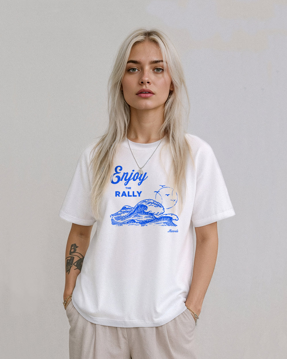 Person wearing a white t-shirt with a blue graphic that reads 'Enjoy the Rally' in text on a plain background