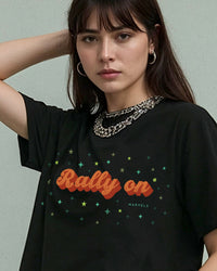 Woman wearing a black tennis t-shirt with 'Rally On' text and star designs, against a plain background.