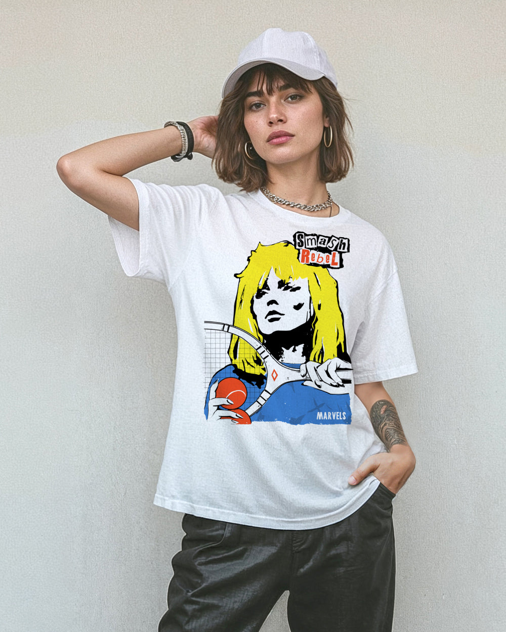Model wearing black pants, a cap and a white t-shirt with a tennis-themed graphic that reads, 'Smash Rebel'.