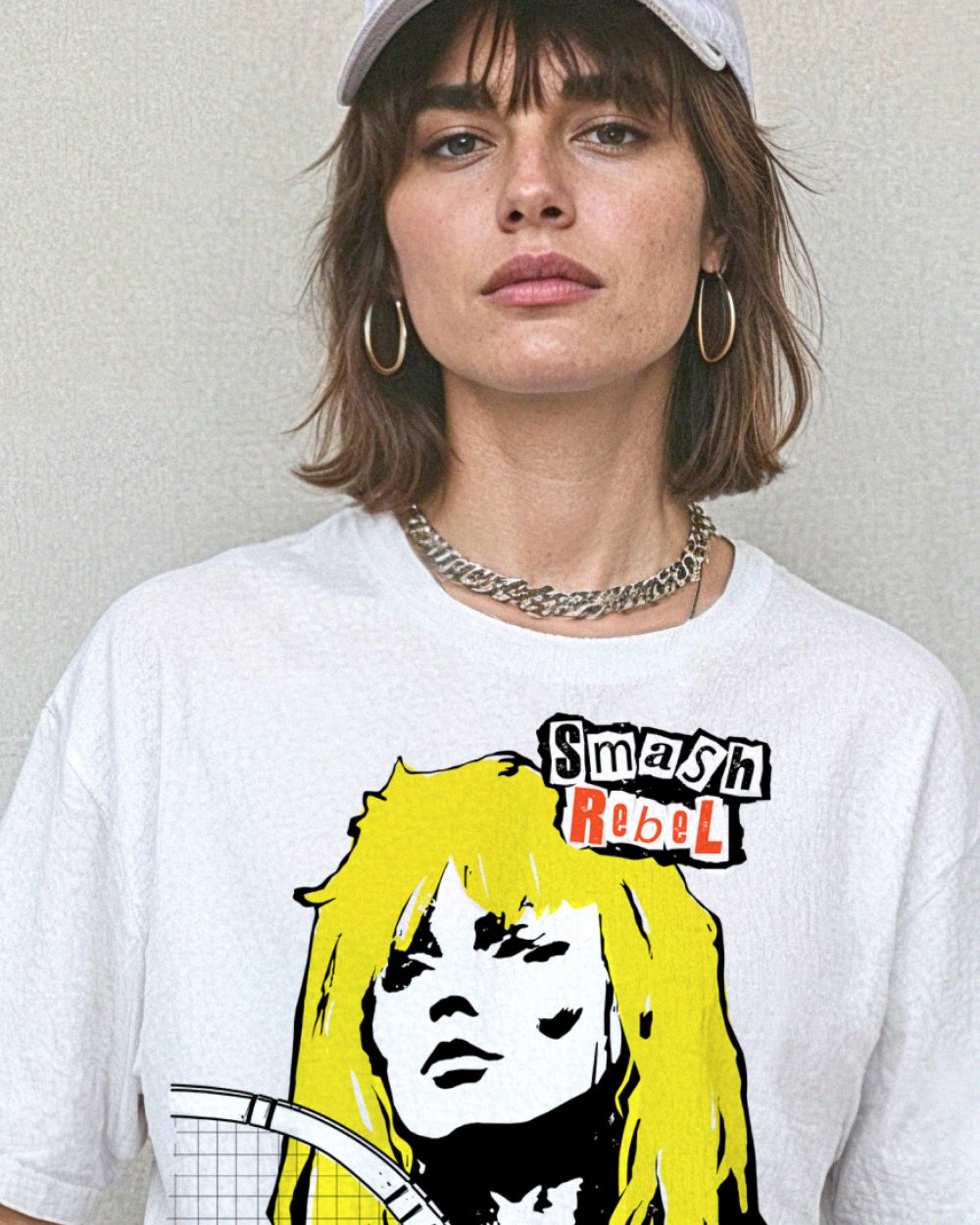 Person wearing a white t-shirt with a tennis-themed graphic that reads, 'Smash Rebel'.