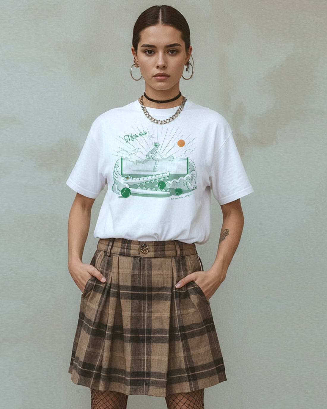 Person wearing a white t-shirt with a tennis player and alligator graphic design and a plaid skirt on a plain background
