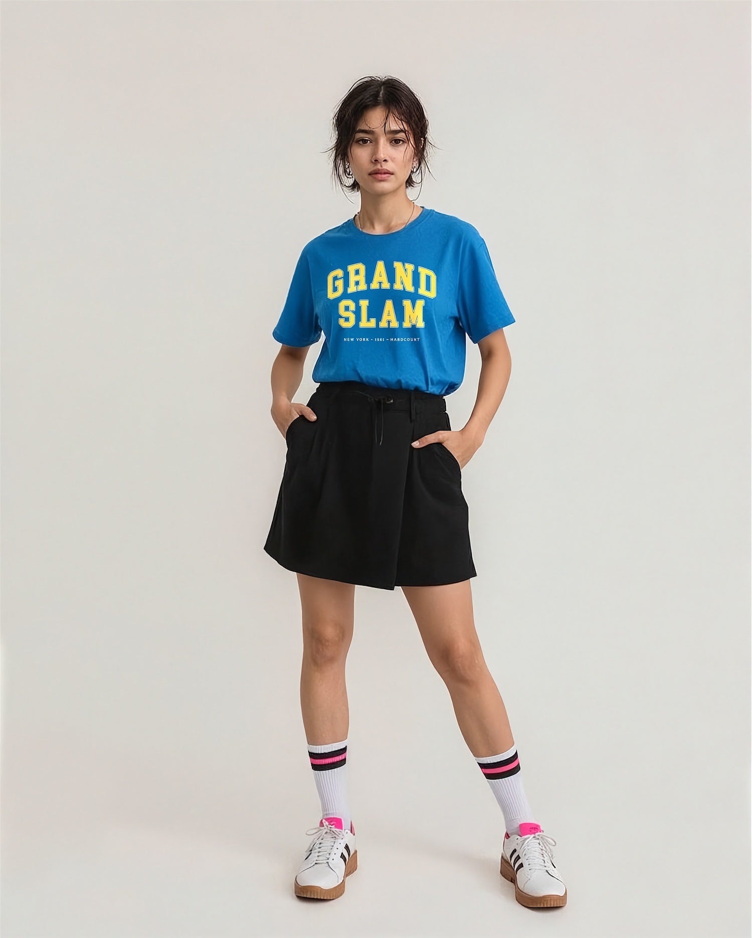 Model wearing a blue 'GRAND SLAM' t-shirt with a black skirt on a plain background
