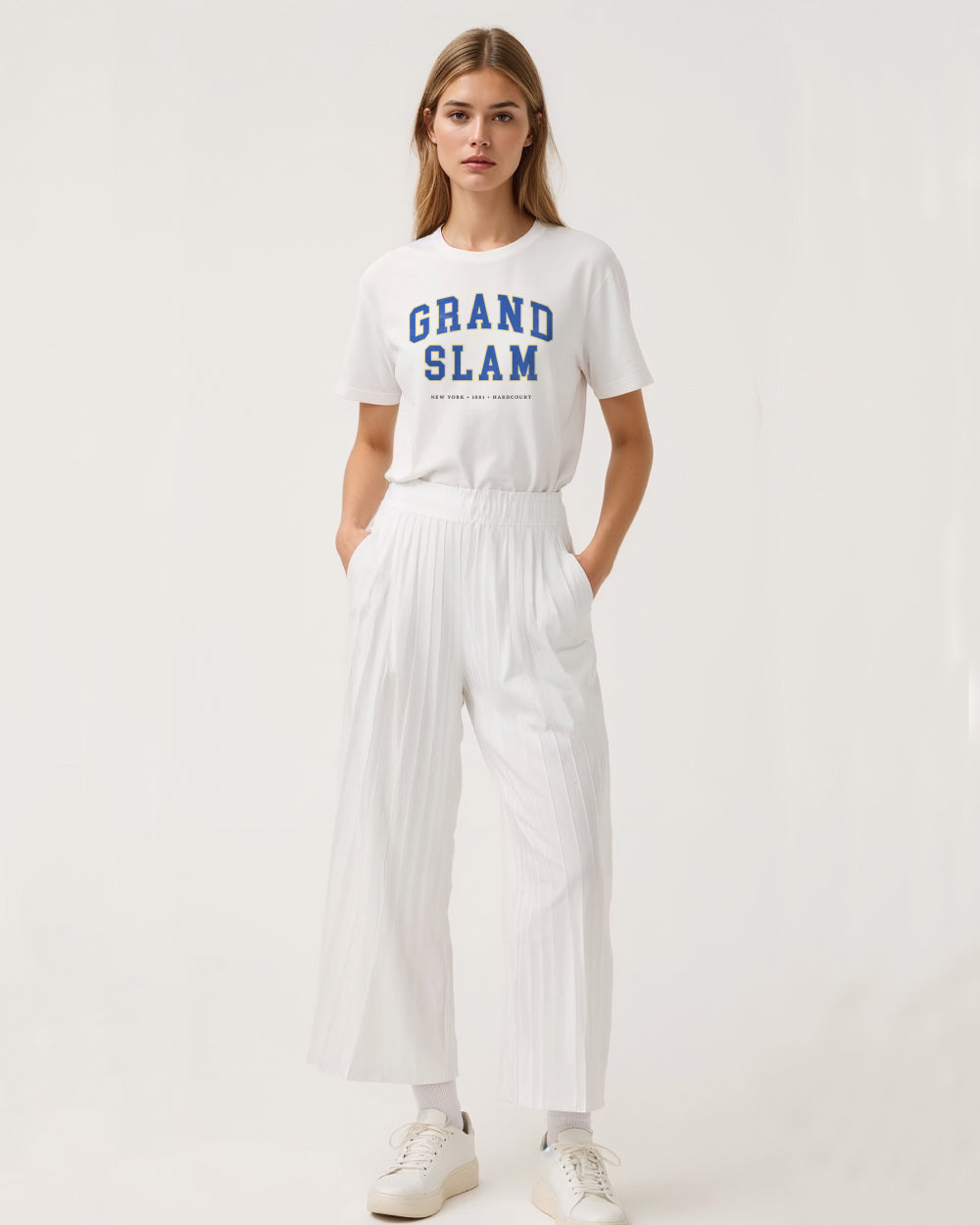 Woman wearing a white 'Grand Slam' t-shirt and white pants on a light background