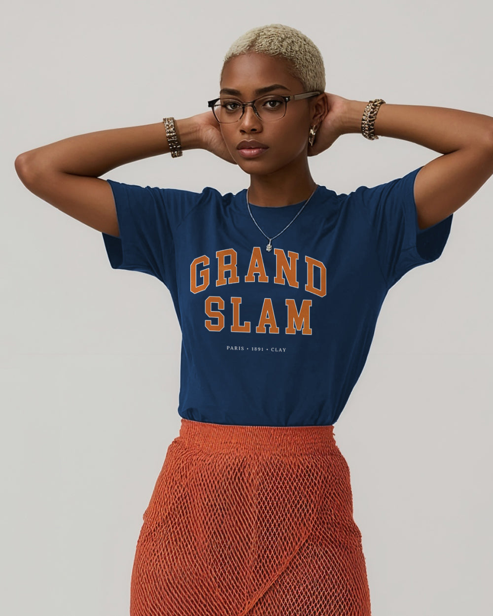Person wearing a blue 'Grand Slam' t-shirt and orange skirt against a plain background
