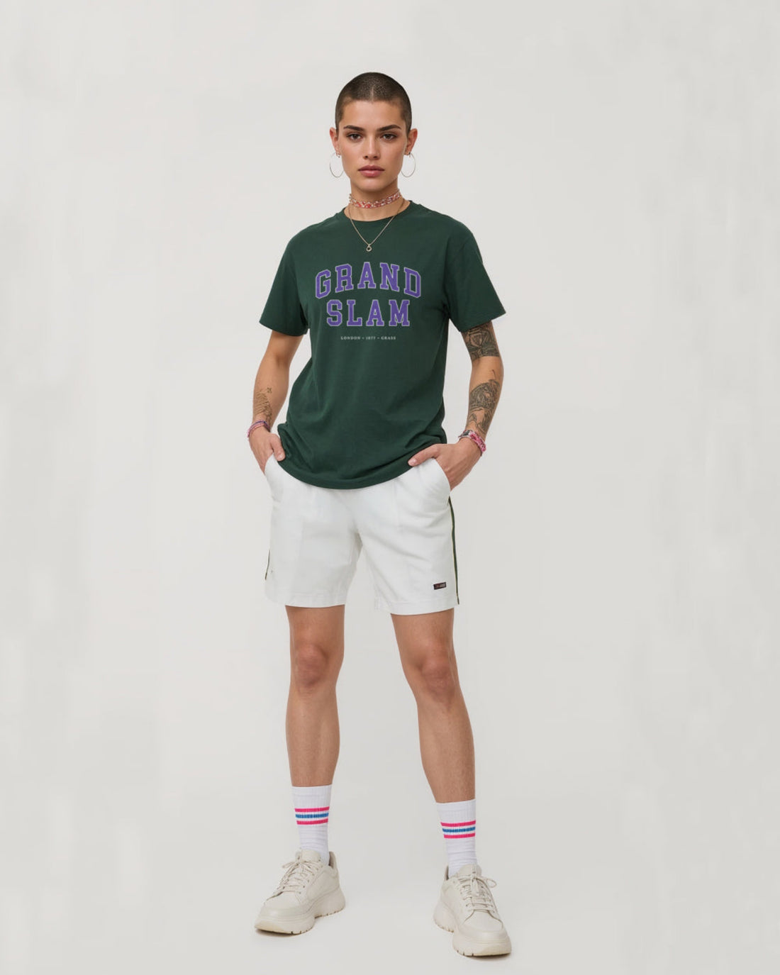 Person wearing a green 'Grand Slam' t-shirt and white shorts on a plain background