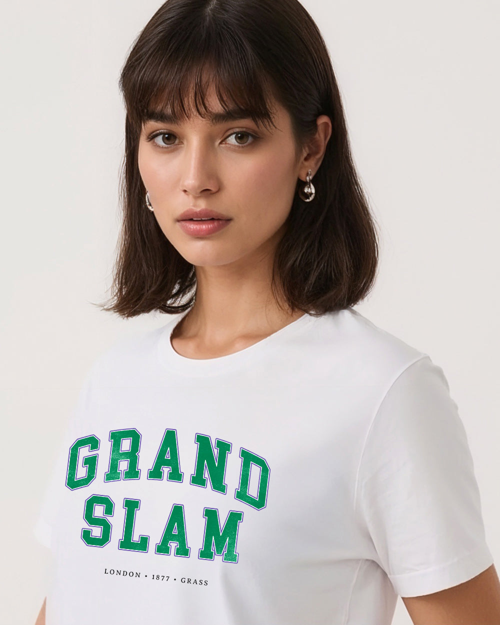 Woman wearing a white t-shirt with 'Grand Slam' text on a plain background