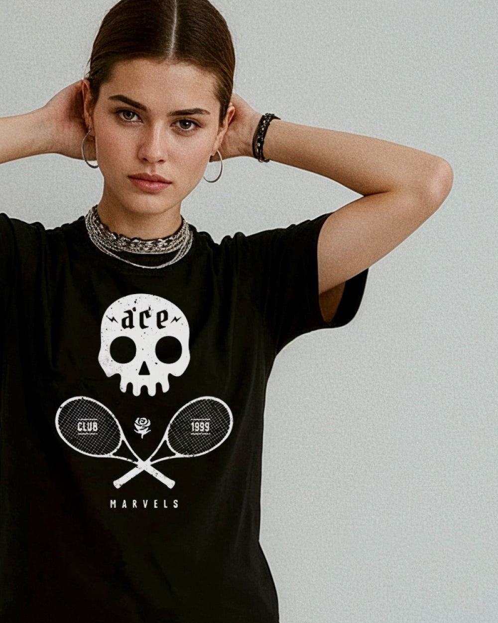 Woman wearing a black t-shirt with a skull and tennis racket design on a plain background