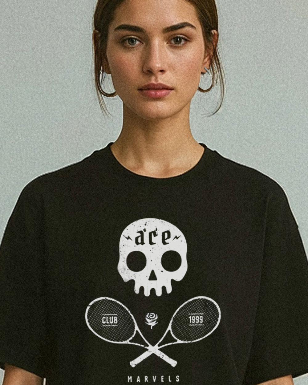 Woman wearing a black t-shirt with a white skull and tennis racket design on a light background