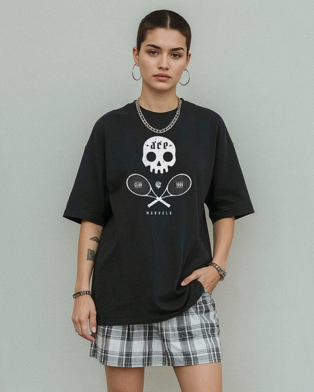 Girl wearing a black t-shirt with a skull and crossed tennis rackets graphic design on a plain background