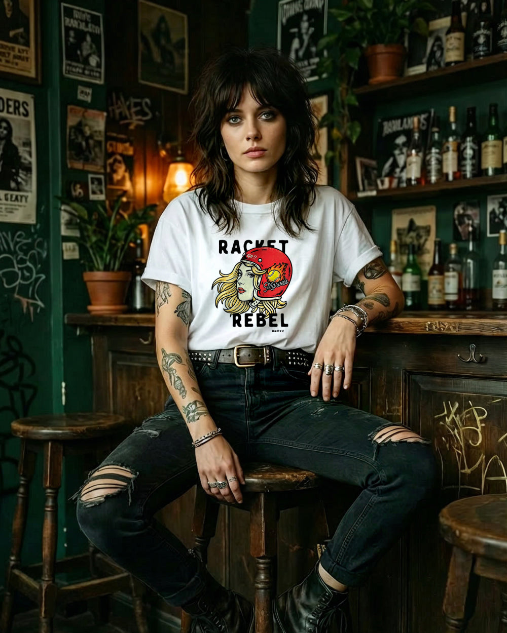 Person wearing a white t-shirt with graphic design sitting in a bar.